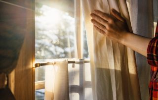 Person opening curtains (Window Energy Efficiency is in The Glass)