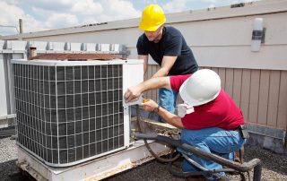 Two workers fixing air conditioning unit