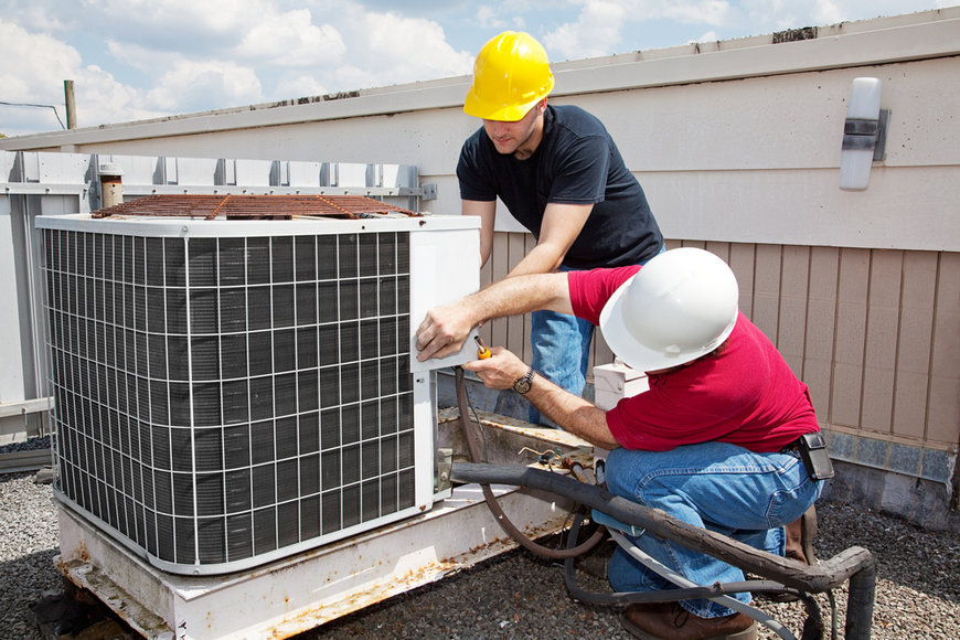 Two workers fixing air conditioning unit