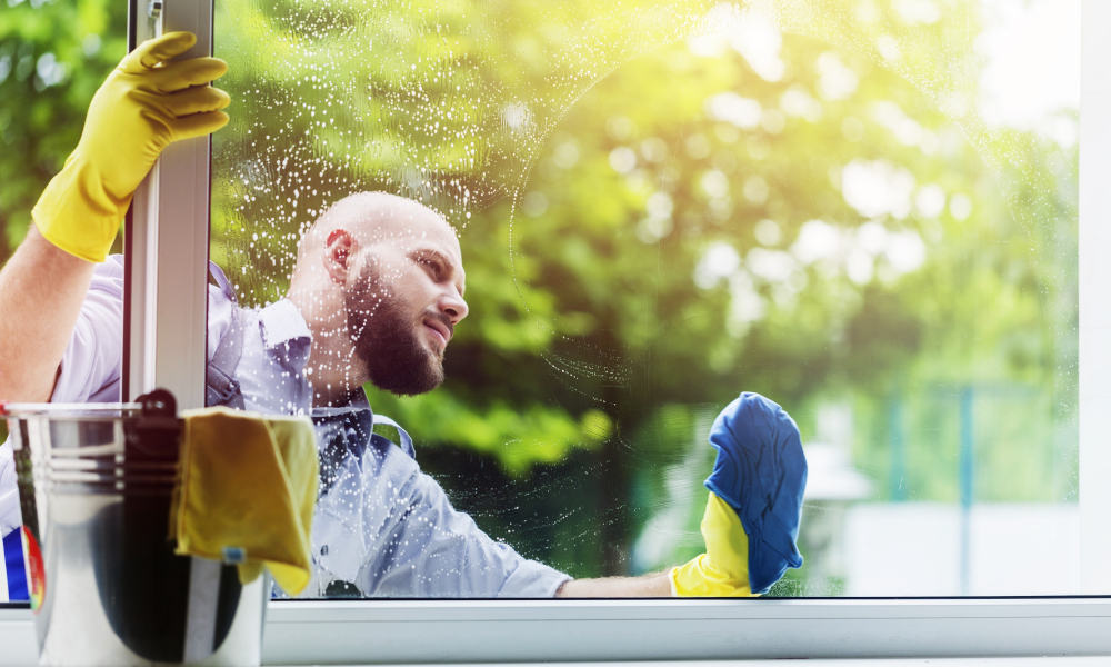 Man cleaning vinyl windows with a cloth and soapy water